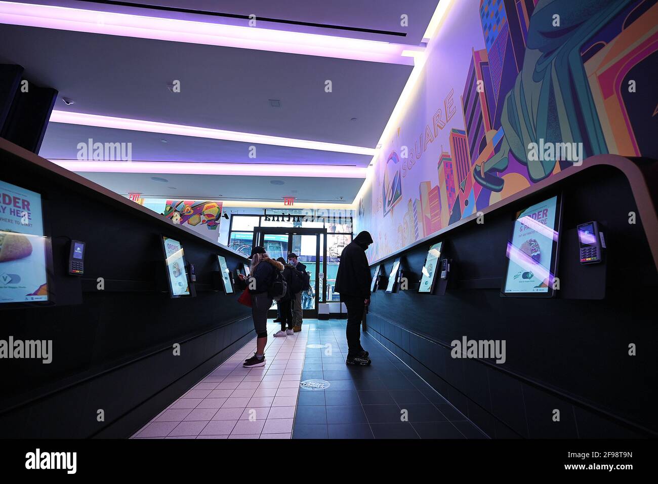 New York, USA. April 2021. Innenansicht des „Digital Only“-Kantinenrestaurants von Taco Bell an der 7th Avenue am Times Square, New York, NY, 16. April 2021. Die Kunden haben Zugriff auf zehn Touchscreen-Menüs, über die sie ihre Lebensmittelbestellungen mit möglichst geringem Kontakt mit Menschen aufgeben und bezahlen können. Die Kunden lassen sich bei der Eingabe die Temperatur überprüfen und werden gebeten, sich für die Kontaktverfolgung in einem Buch zu registrieren. (Foto von Anthony Behar/Sipa USA) Quelle: SIPA USA/Alamy Live News Stockfoto