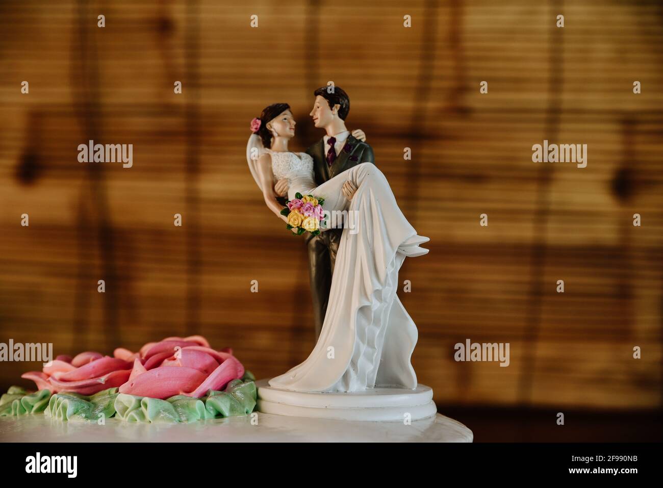 Schöne Figur eines Bräutigams, der eine Braut auf den hebt Hochzeitstorte als Dekoration Stockfoto
