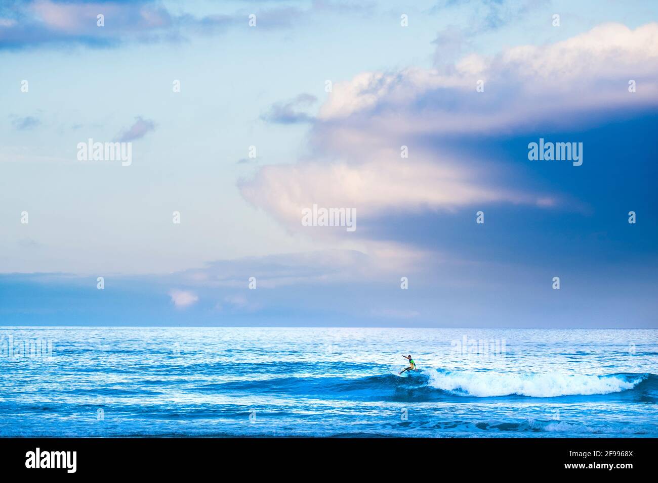 Surfer Tourist Athlet tun Surfen Wassersport Aktivität allein in Die blauen Wellen des Ozeans - farbenfroher Himmel im Hintergrund und Konzept der gesunden tapferen Menschen in extremen Lebensstil Freizeit Stockfoto