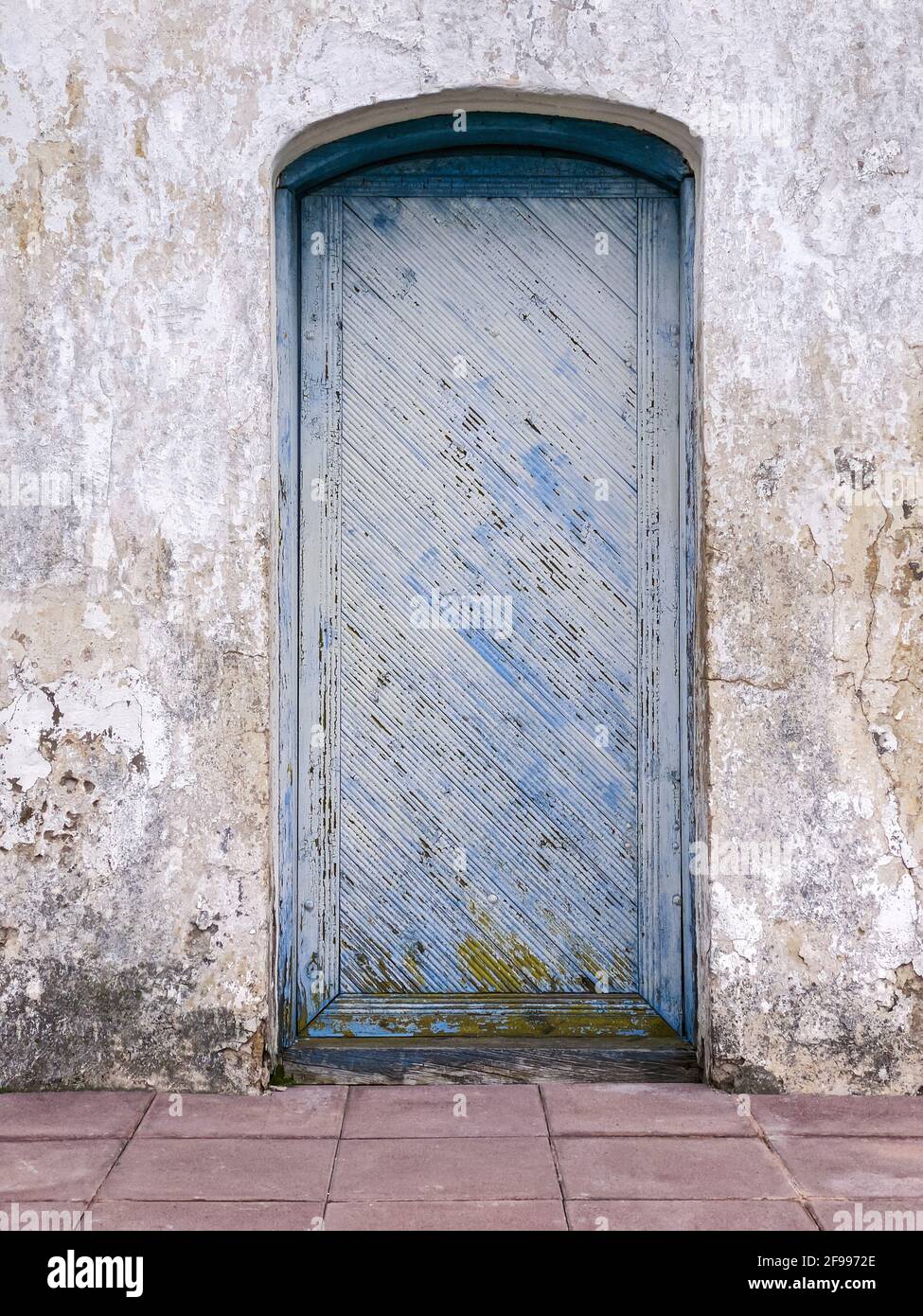 Holztür mit abblätternder blauer Farbstruktur auf grauem Stuck Wand Stockfoto