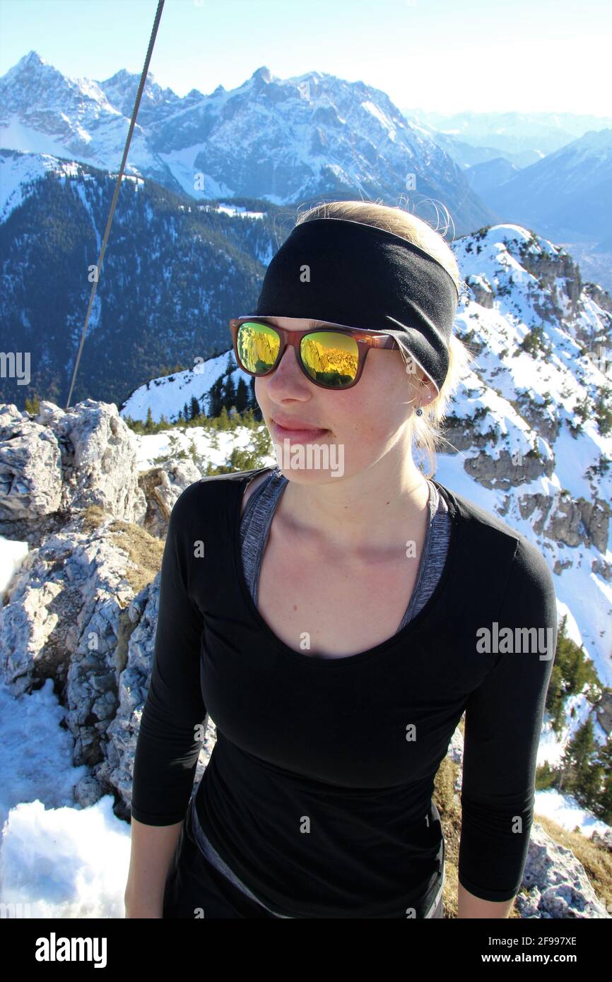 Junge Frau auf Winterwanderung zum Signalkopf (1895 Meter) im Hintergrund die Wörner, Tiefkarspitze und das Karwendelgebirge, Europa, Deutschland, Bayern, Oberbayern, Isartal, Krün Stockfoto