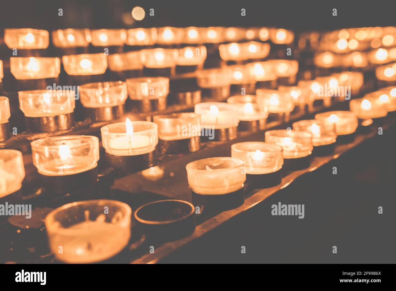 Teelichter und kleine Kerzen in einer Kirche - Hingabe Und Gebet Stockfoto