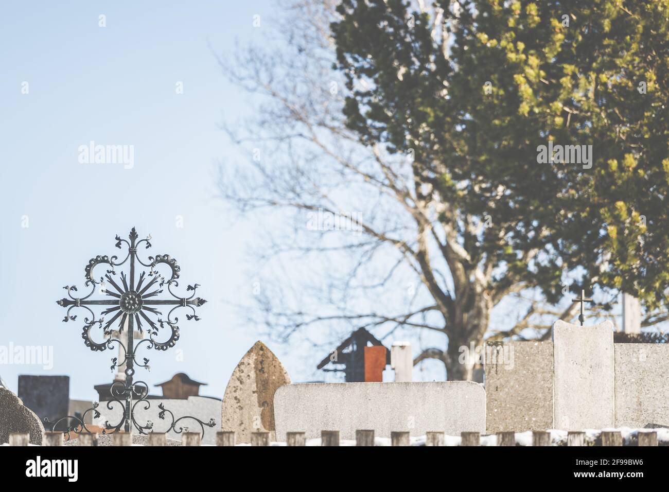Ein schmiedeeisernes Metallkreuz auf einem Friedhof in den bayerischen Bergen. Stockfoto