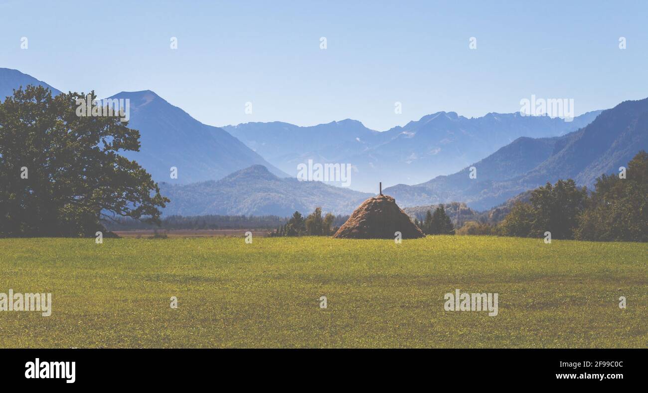 'Strahlrischen', ein Heuhaufen im Murnauer Moos vor der Kulisse der Alpen mit Zugspitze und Alpspitze. Bergpanorama Stockfoto