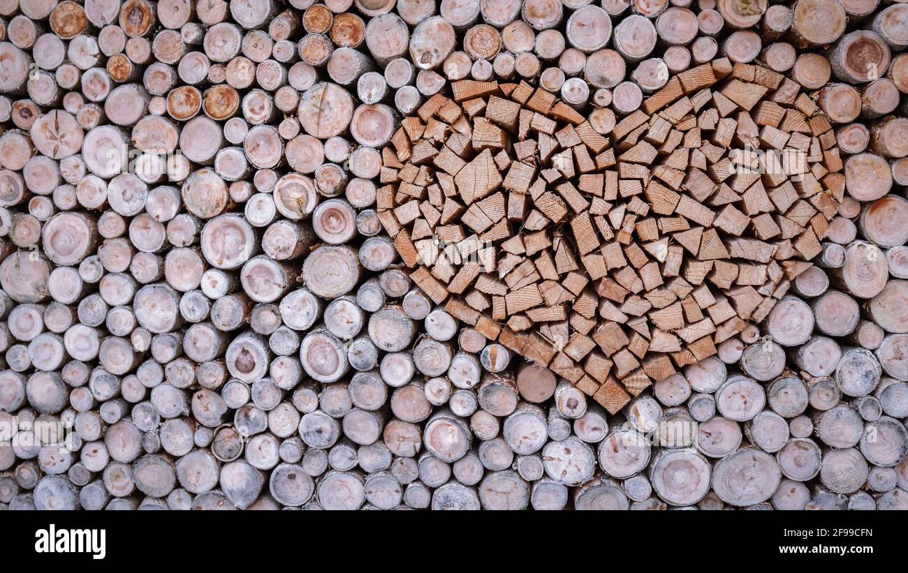 Ein Holzherz, gestapelt in einem Stapel Brennholz für den Kamin oder Holzofen. Stockfoto
