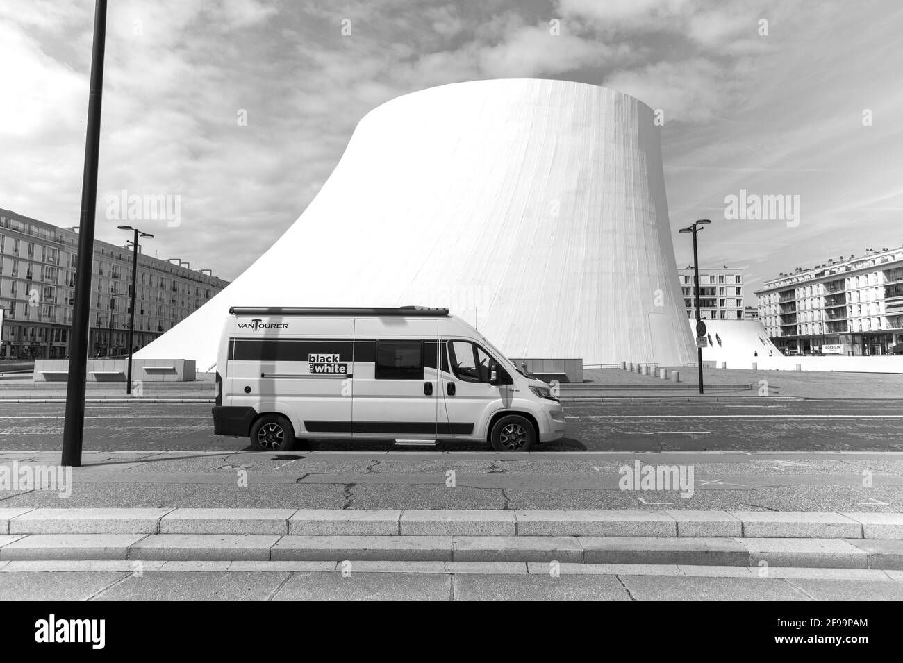 Wohnmobil / Van 'Vantourer Black and White' vor Le Volcan, ein Kulturkomplex mit Konzertsaal und Bibliothek, entworfen vom berühmten Architekten Oscar Niemeyer - mitten in Le Havre, Frankreich Stockfoto