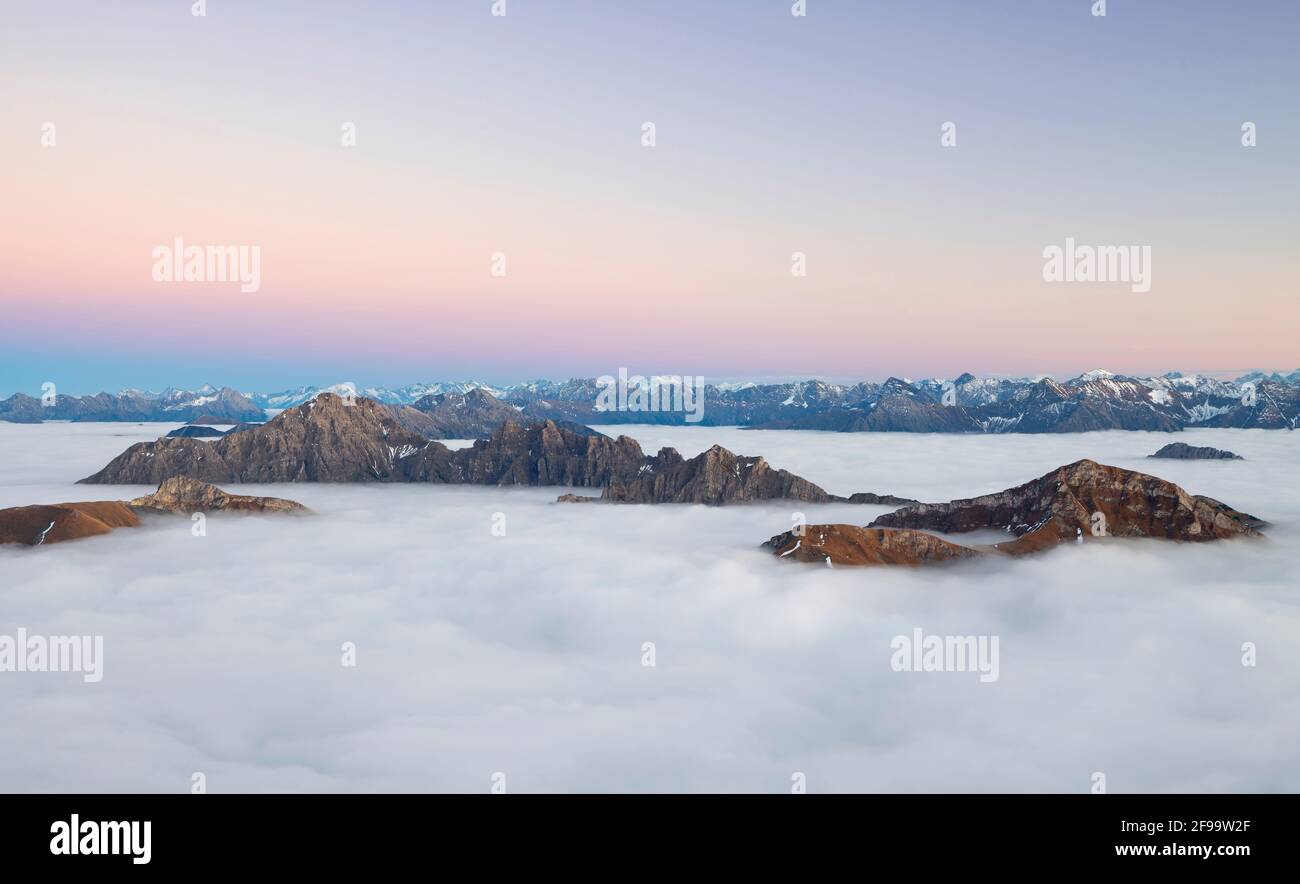 Nach Sonnenuntergang ragen Berggipfel aus dem Wolkenmeer bei Tannheim in den Allgäuer Alpen (Leilachspitze, Lachenspitze, Rote Spitze). Im Hintergrund die Lechtaler Alpen. Tirol, Österreich, Europa Stockfoto