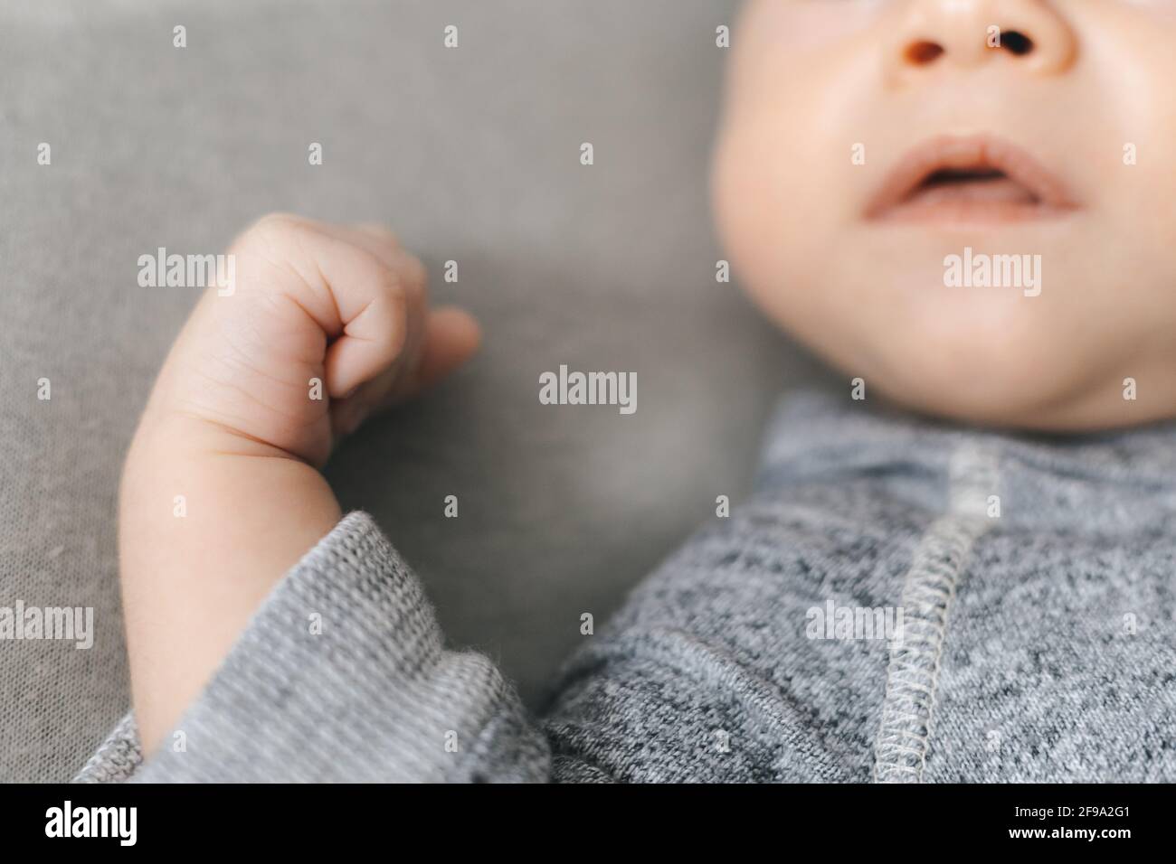 Verkürzter Rahmen aus Neugeborenem, Nase, Mund und kleiner Hand in Rahmen, glückliches Elternschaftskonzept Stockfoto