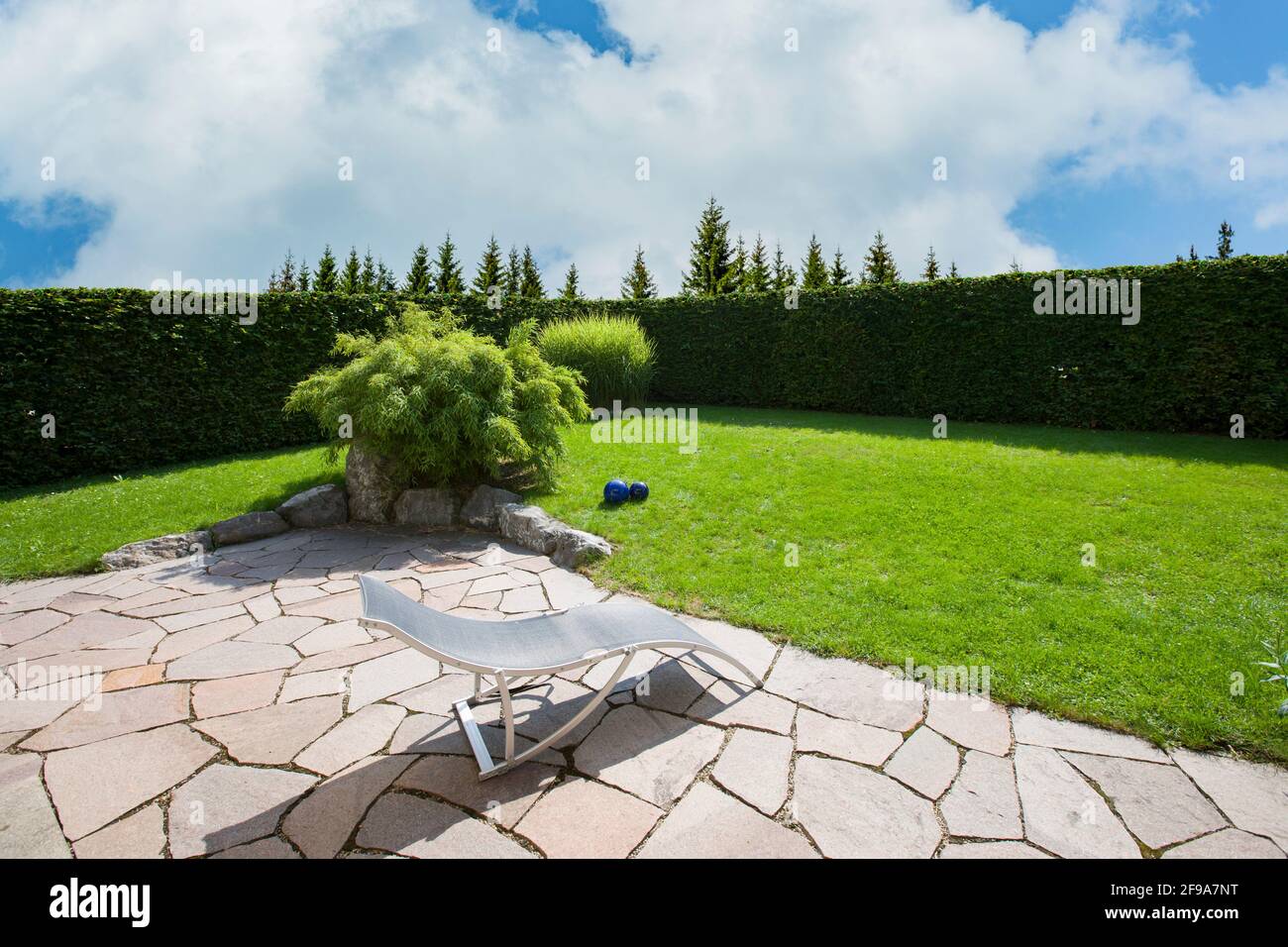 Natursteinterrasse mit einem grünen Garten Stockfoto