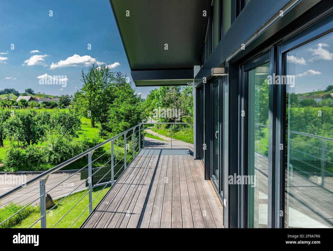 Fensterfront mit Holzterrasse auf einem Einfamilienhaus in Das Grün Stockfoto