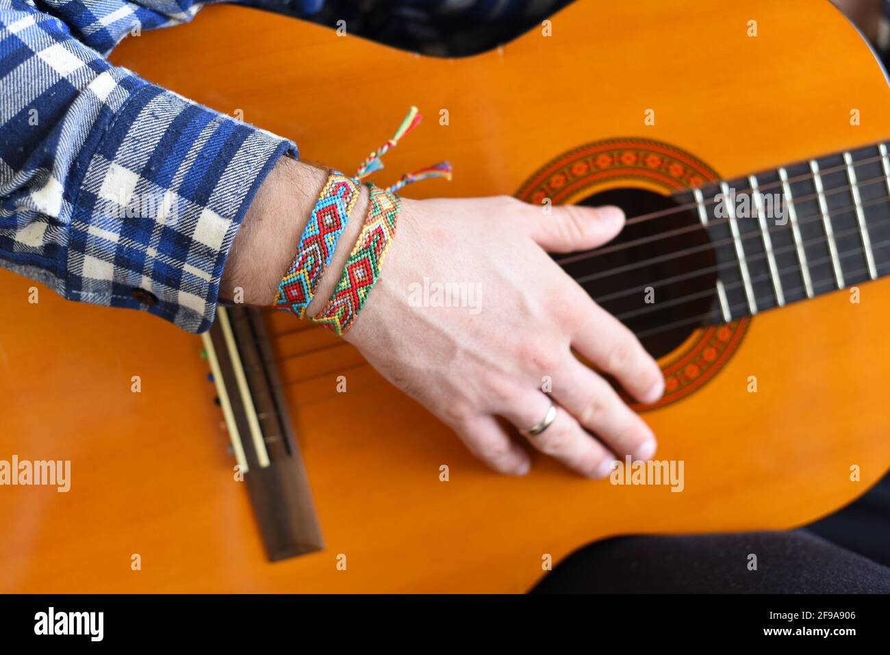 Freundschaftsarmbänder mit indischem Muster am Handgelenk des Gitarristen Stockfoto