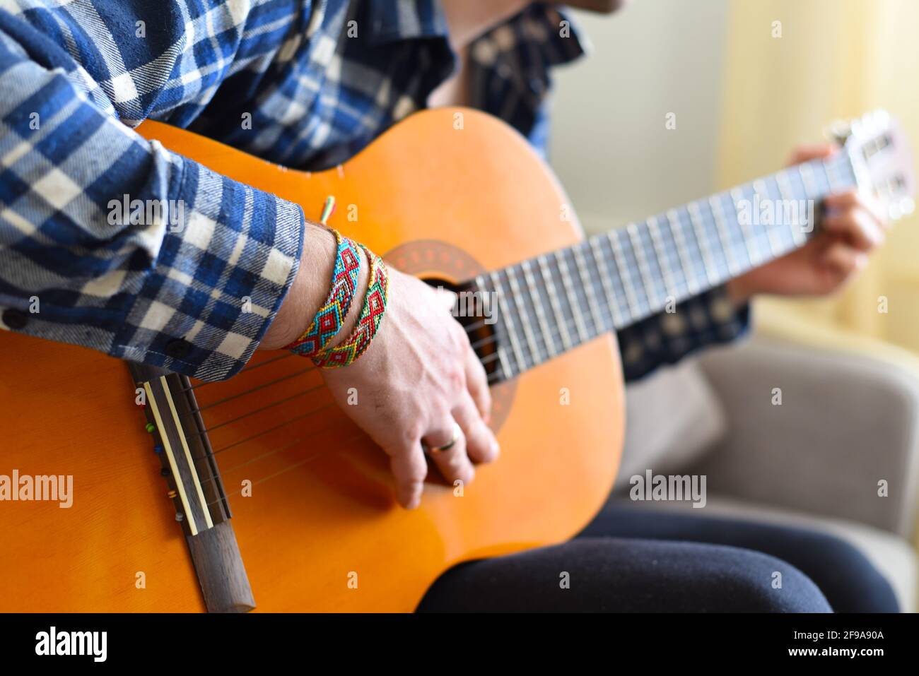 Freundschaftsarmbänder mit indischem Muster am Handgelenk des Gitarristen Stockfoto