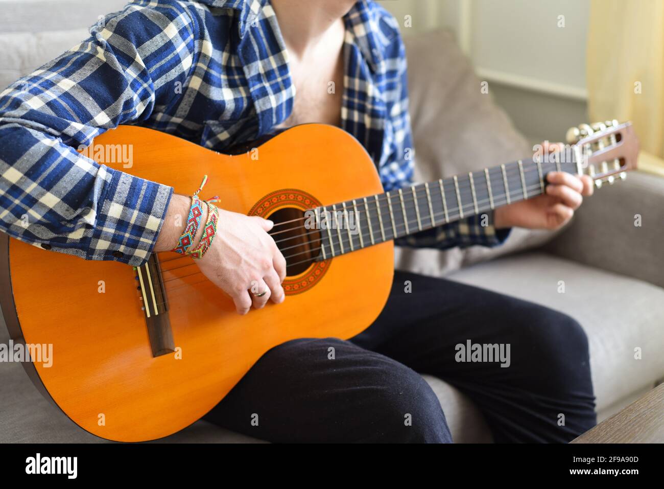 Freundschaftsarmbänder mit indischem Muster am Handgelenk des Gitarristen Stockfoto