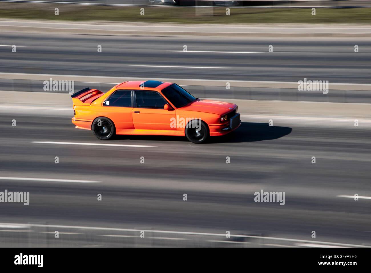 Ukraine, Kiew - 3. März 2021: Orangefarbenes Modell des BMW E30 M3, das sich auf der Straße bewegt; Stockfoto