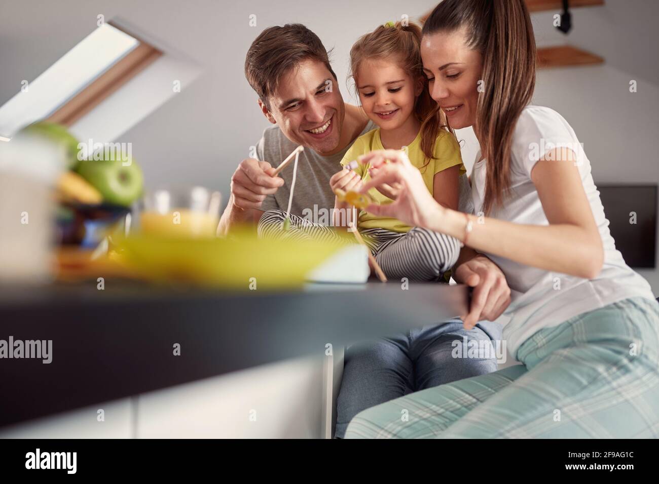 Eine junge Familie, die sich nach einem Frühstück in einer fröhlichen Atmosphäre zu Hause gut Vergnügen kann. Familie, Frühstück, zusammen, Zuhause Stockfoto
