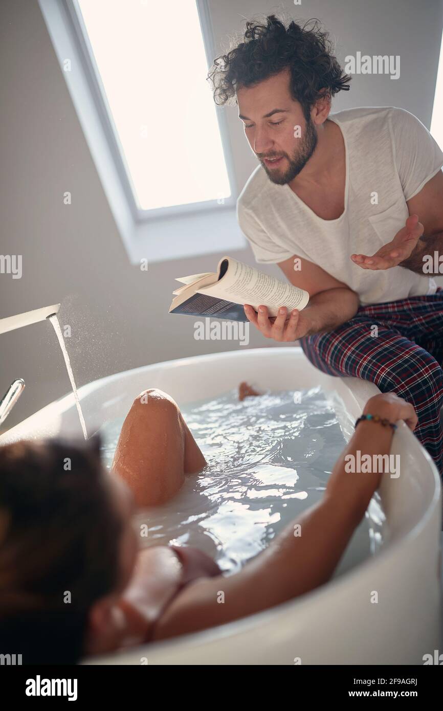 Romantischer Moment eines hübschen kaukasischen Paares im Badezimmer. beardy gut liest seinem schüchternen Partner in der Badewanne ein Buch und teilt sich einen Moment. Valentin Stockfoto