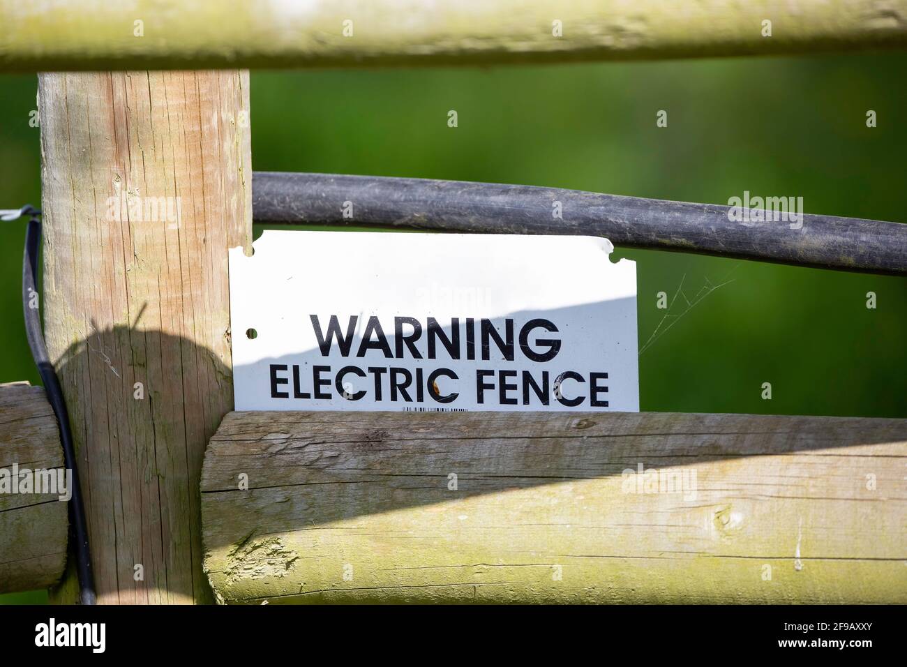 Ein Warnschild an einem elektrischen Zaun auf Ackerland Stockfoto