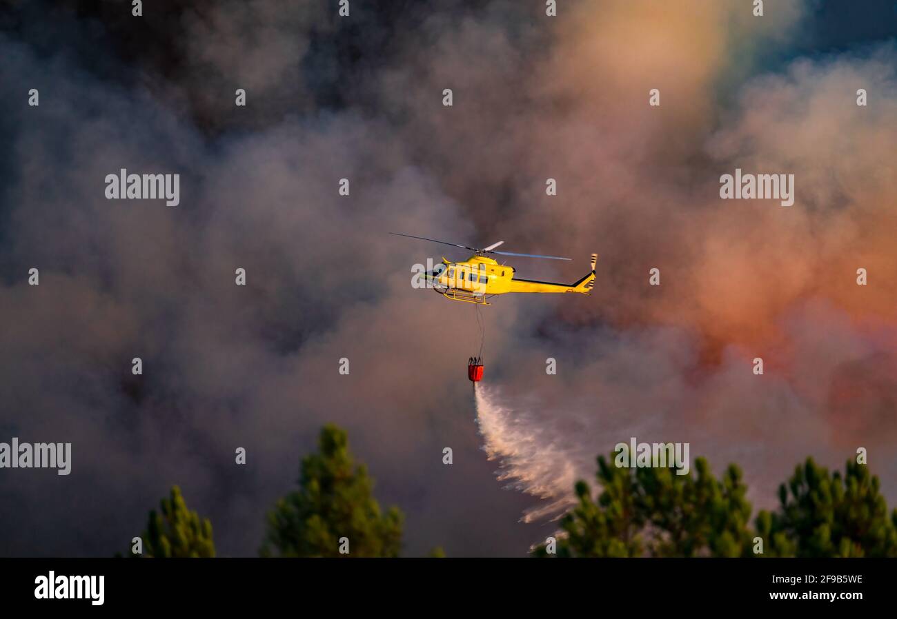 Hubschrauber wirft einen Eimer Wasser ins Feuer Stockfoto