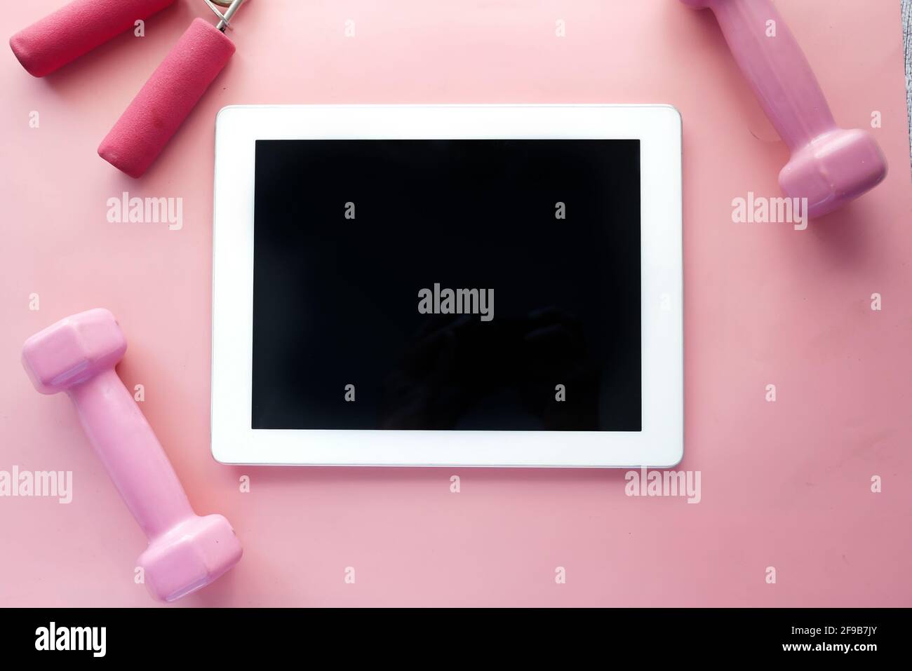 Digitales Tablet mit Sportausrüstung auf rosa Hintergrund Stockfoto