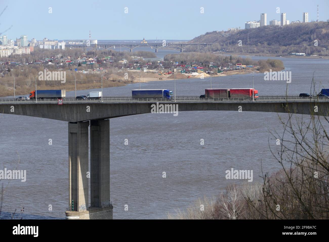 Große Lastwagen fahren über die Brücke über den Fluss in der Stadt. Stockfoto