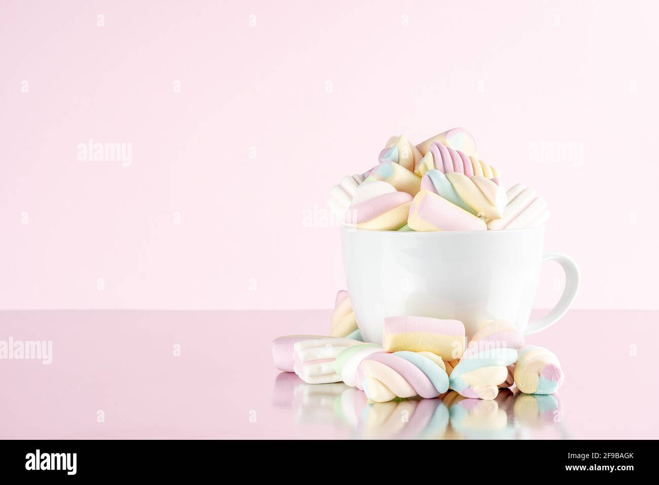 Marshmallows bunte Kaubonbons in einer Tasse auf rosa Hintergrund. Sweet Holiday Food Konzept. Stockfoto