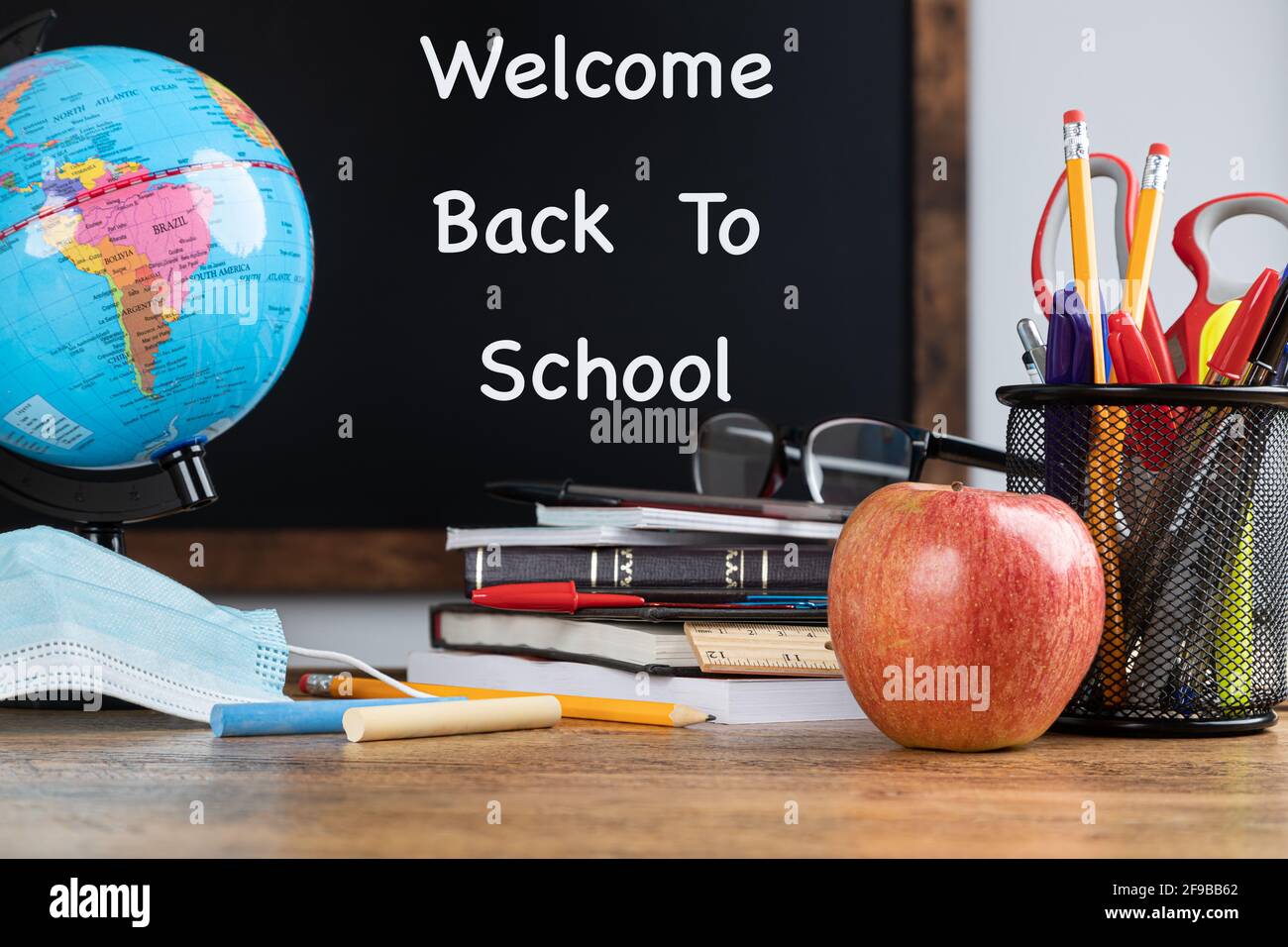 Klassenraum Schulschreibtisch mit Welcome Back to School Text geschrieben Auf der schwarzen Tafel im Hintergrund Stockfoto