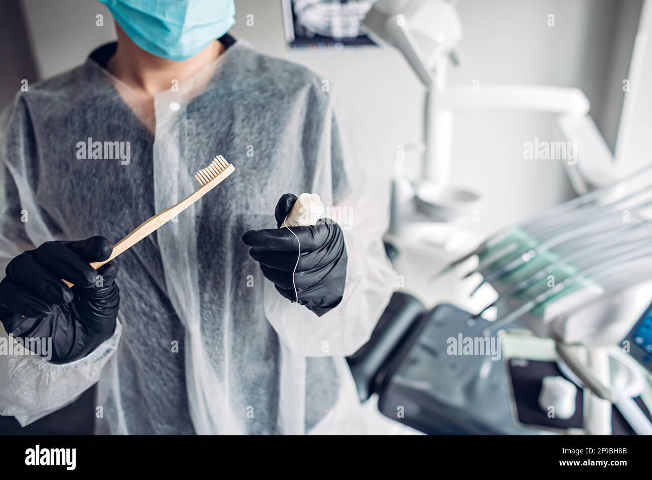 Zahnarzt zeigt einfachste und wichtigste Mittel der Prävention für Mundgesundheit - Zahnbürste und Zahnseide Stockfoto