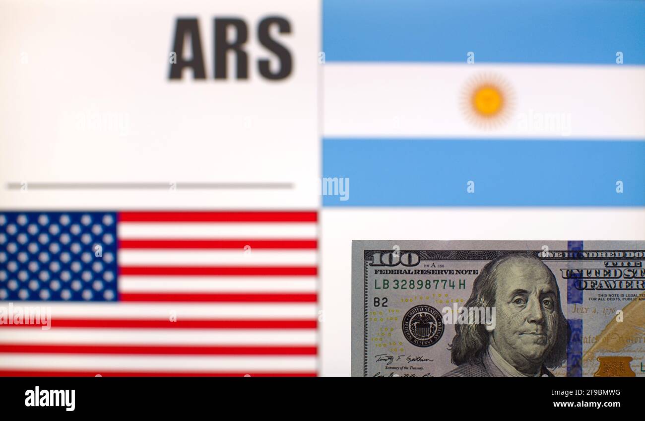 100 US-Dollar Banknote auf verschwommenem Hintergrund der argentinischen und US-amerikanischen Flaggen und des Währungscodes Argentiniens. Wechselkursvorlage Stockfoto