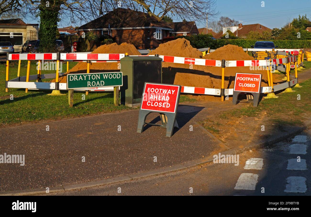 In einem Wohngebiet in Hellesdon, Norfolk, England, Großbritannien, wurden Erdhaufen gelagert, die bei Versorgungsgrabungen mit geschlossenen Hinweisschildern gelagert wurden. Stockfoto