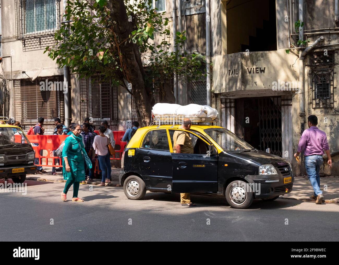 Taxi mit Taschen auf dem Dachgepäckträger hält vor dem alten Apartmentgebäude in Mumbai-Dadar, Maharashtra, Indien, Asien. Stockfoto