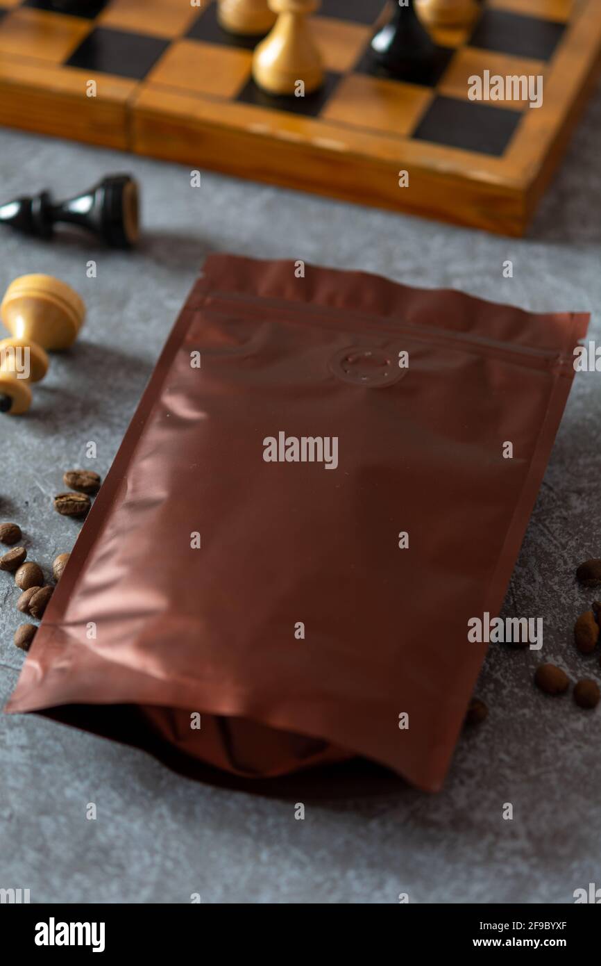 Leere Kaffeeverpackungen mit Entgasungsventil, Kaffeebohnen und Schach, Kaffeeverpackungen Mockup mit leerem Raum, um Ihr Branding-Design zu zeigen. Stockfoto