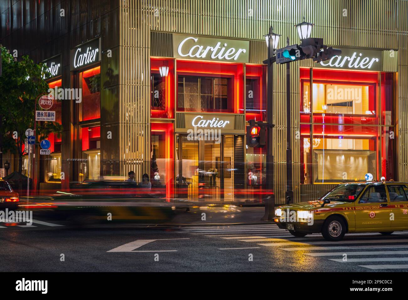 Japanisches Taxi, das an der goldenen Fassade des Cartier-Geschäfts in der Abenddämmerung vorbeifährt, Ginza, Tokio, Japan Stockfoto