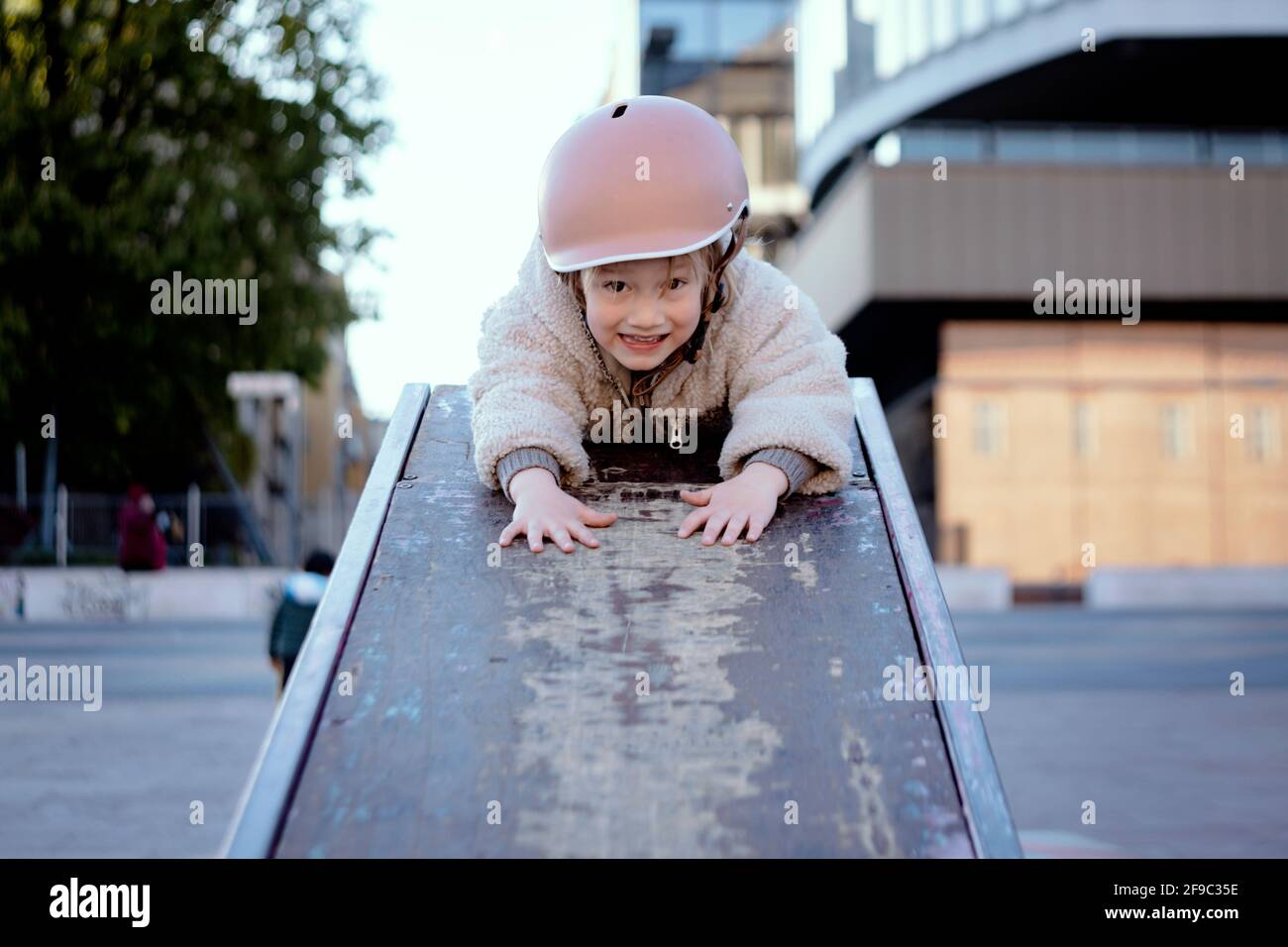Kleines Mädchen 4 Jahre alt im Skatepark lächelnd In einem Helm Stockfoto