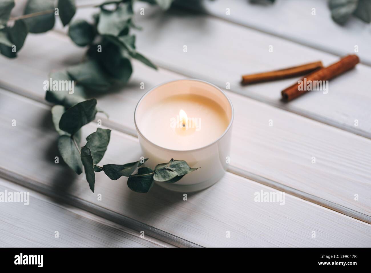 Kerze, Eukalyptus, Zimt auf weißem Holzhintergrund Stockfoto