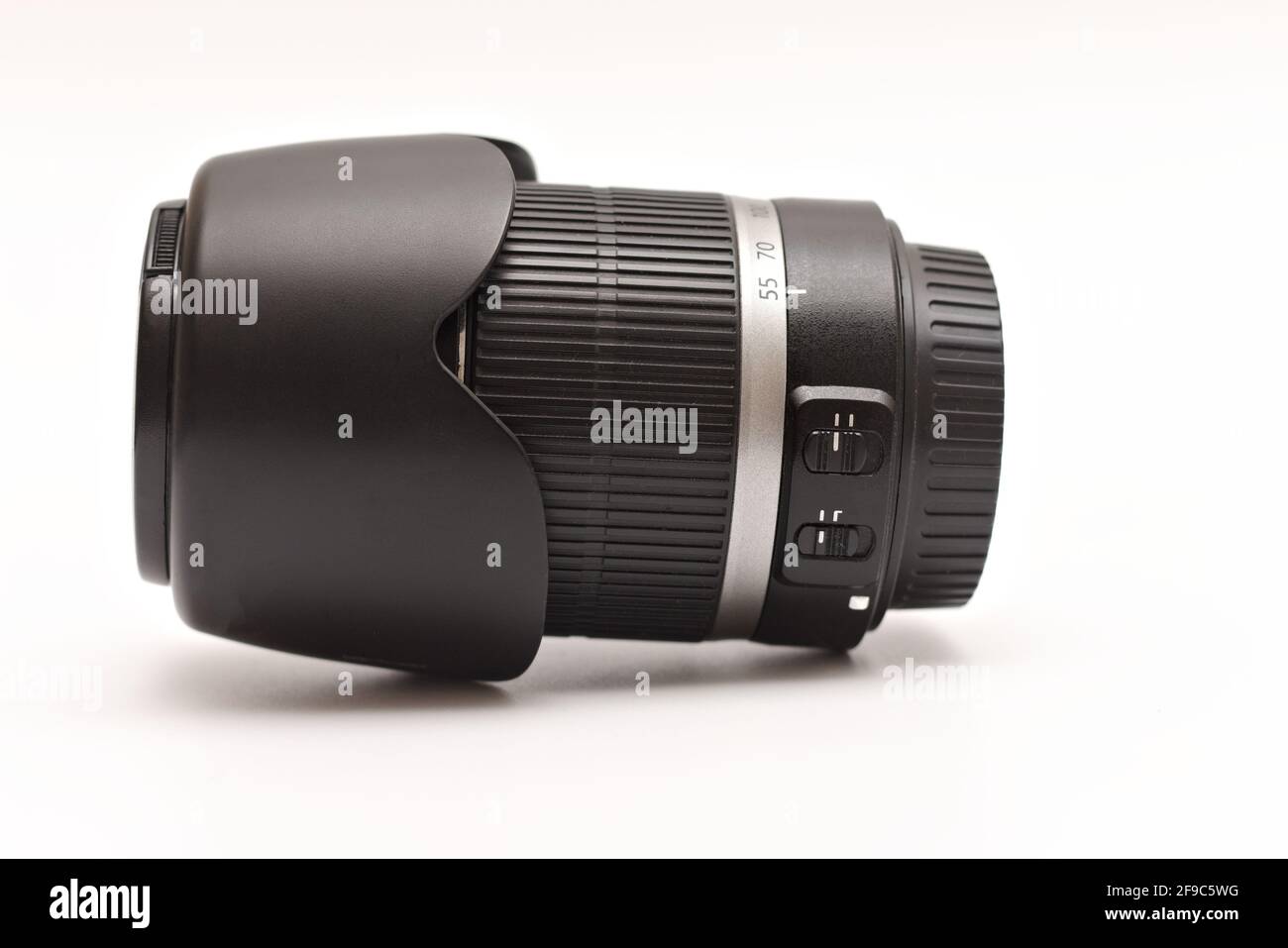 Großes, schwarzes Zoomobjektiv für DSLR-Kameras mit Kapuze Auf einer weißen Oberfläche Stockfoto