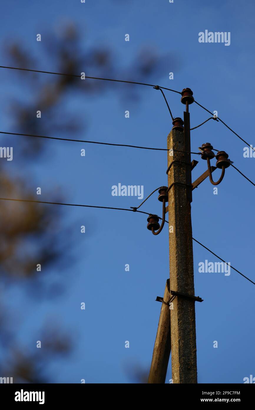 Alte Säule mit Drähten auf dem blauen Abendhimmel Hintergrund Stockfoto