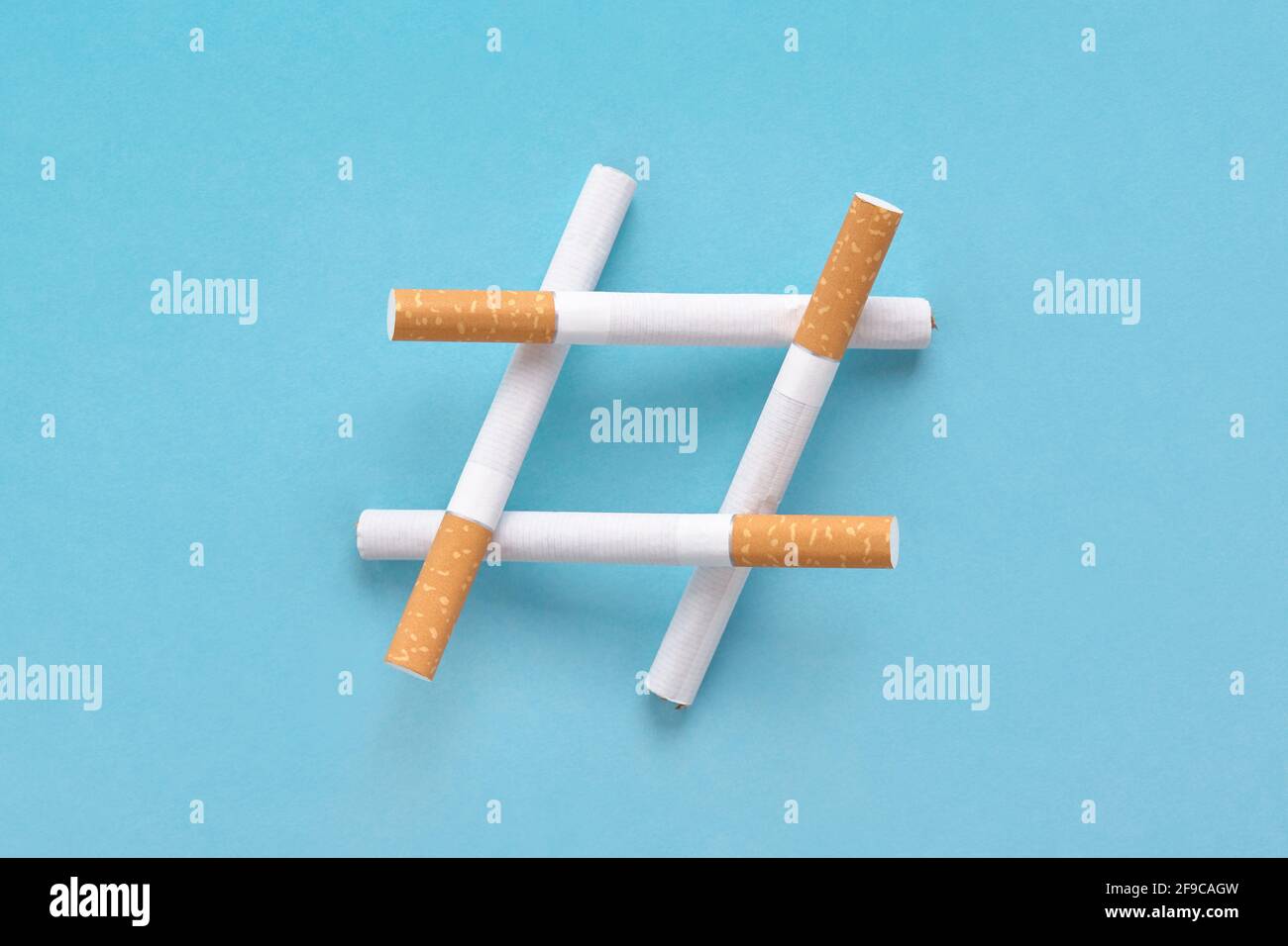 Hashtag-Schild aus Zigaretten auf blau, Symbol für Nichtraucher oder kein Tabaktag. Stockfoto Hashtag-Schild aus Zigaretten auf blau, Symbol für Nichtraucher oder kein Tabaktag. Stockfoto