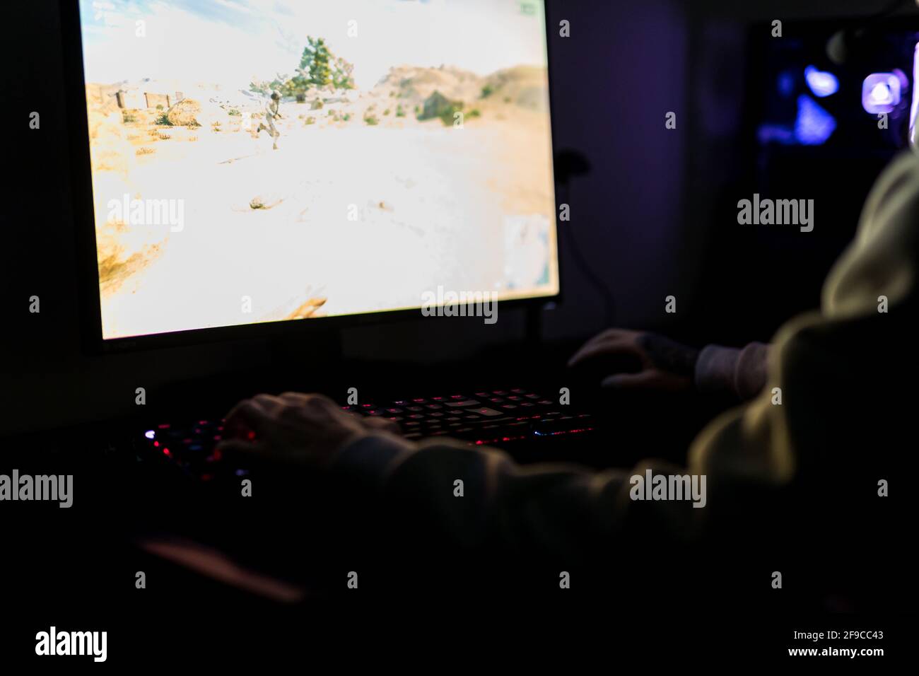 Professioneller Gamer oder Streamer, der Ego-Shooter-Online-Videospiel auf einem speziell angefertigten Gaming-PC spielt. Er trägt ein Headset Stockfoto