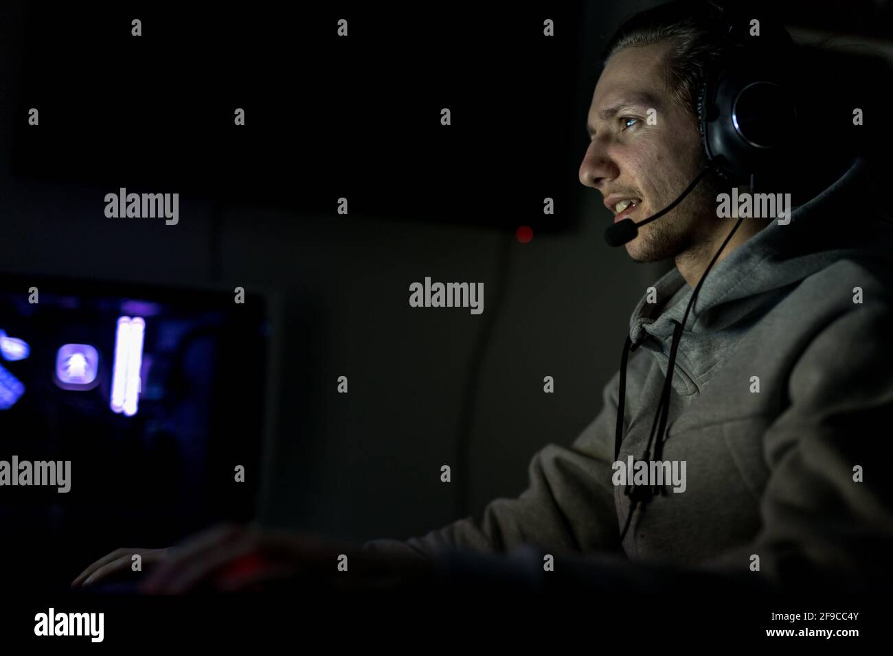 Professioneller Gamer oder Streamer, der Ego-Shooter-Online-Videospiel auf einem speziell angefertigten Gaming-PC spielt. Er trägt ein Headset Stockfoto