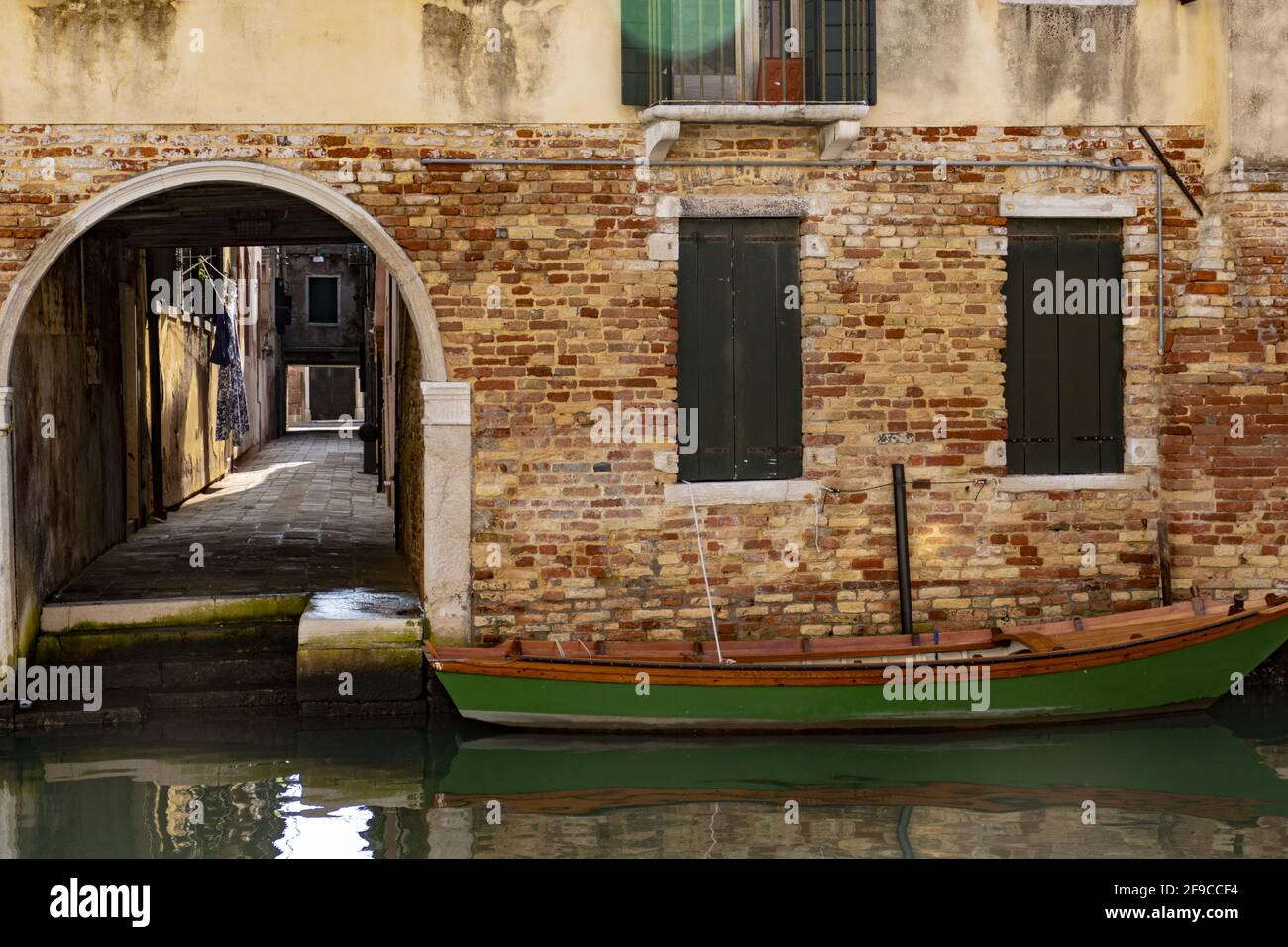 Kanu und Bogeneingang in einer Backsteinmauer auf einem Kanal in Venedig, Italien Stockfoto