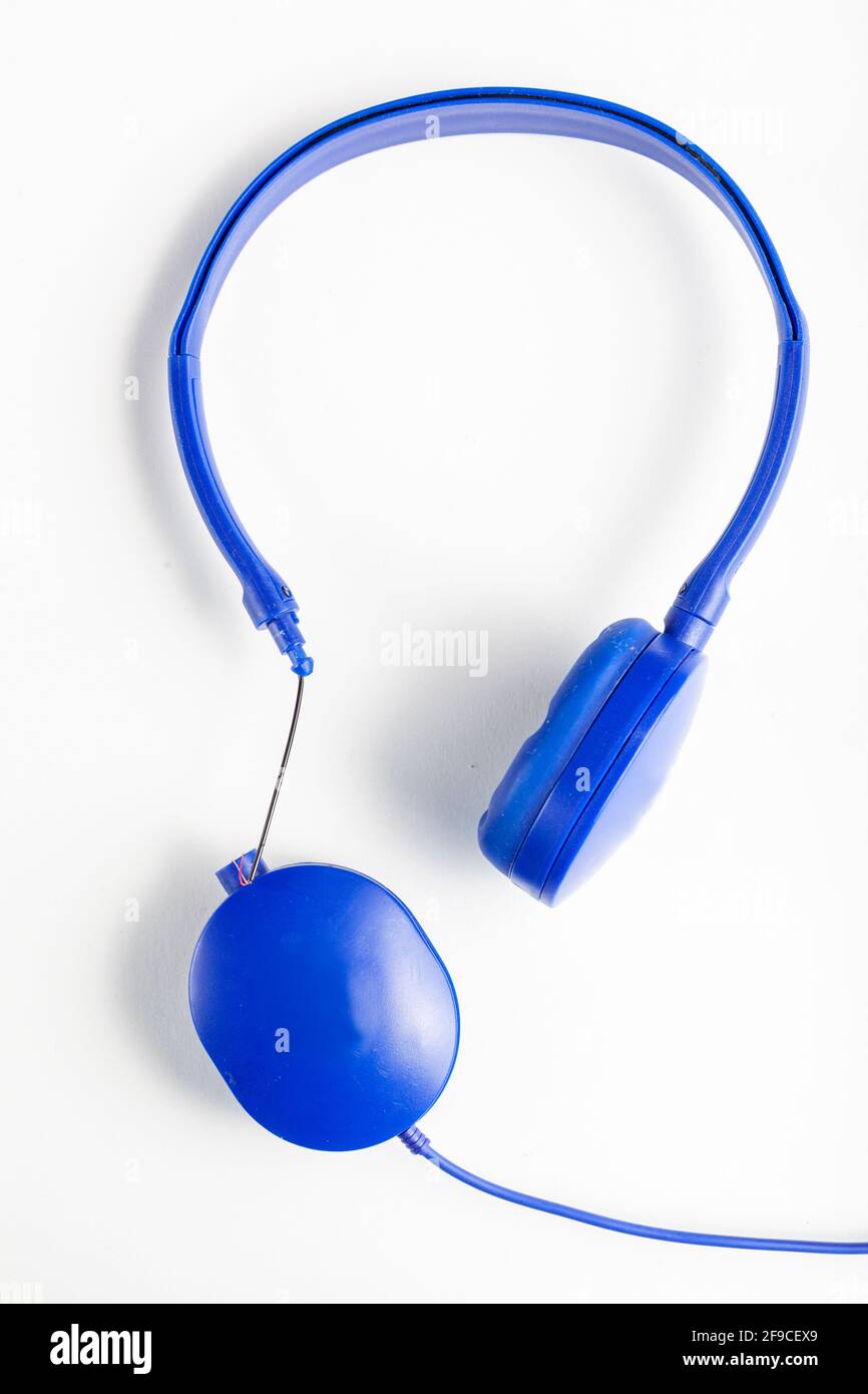 Isoliertes Bild eines blauen Kopfhörers mit einstellbarem Kopfband. Eines der Ohrstücke ist an der Verbindungsseite gebrochen, die Kabel sind freigelegt. Konzeptbild Stockfoto