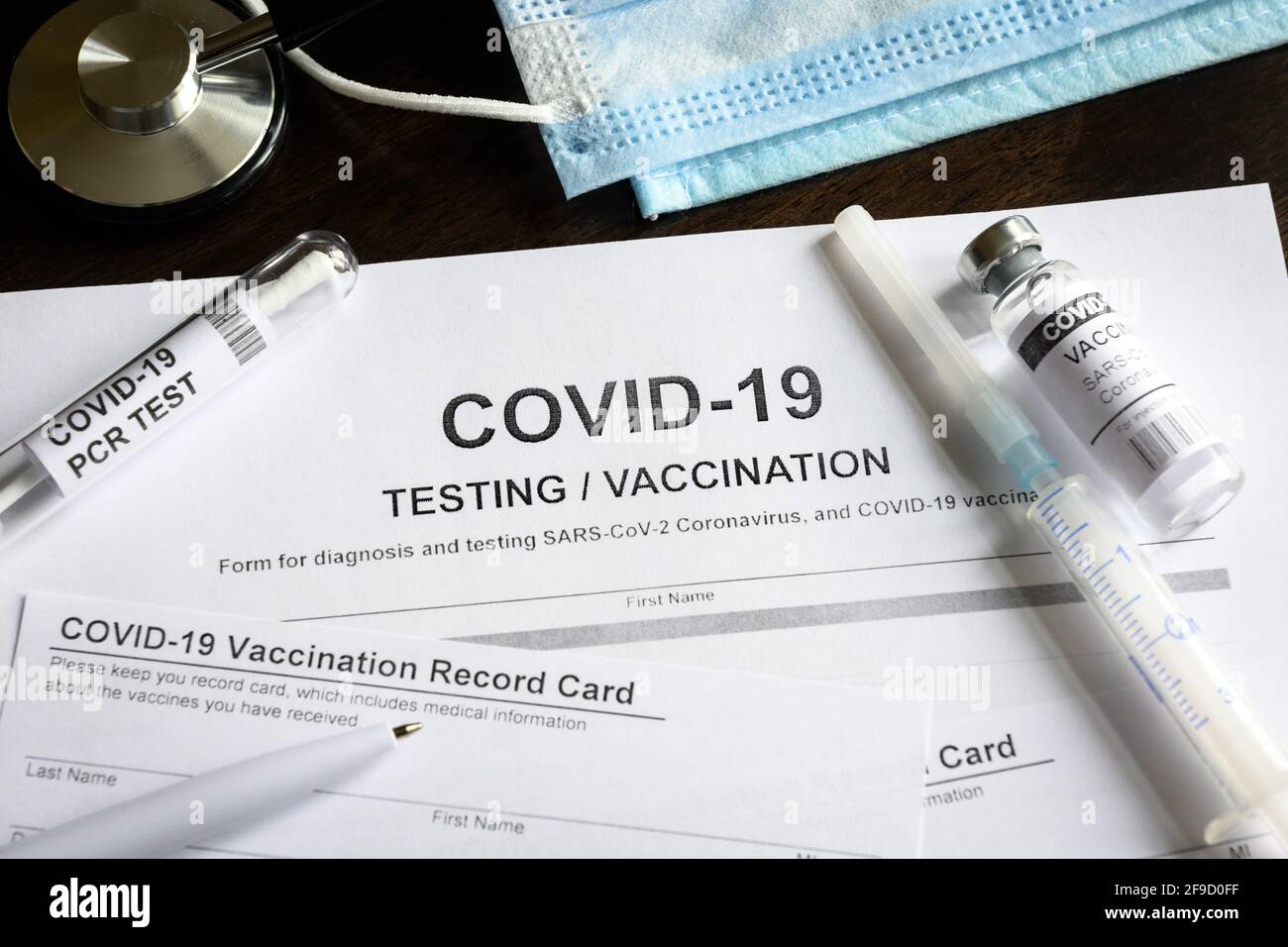 COVID-19-ärztliche Untersuchung und Impfung am Schreibtisch, Injektionspaket für Coronavirus-Impfstoff und Impfpass am Schreibtisch. Konzept des Corona-Virus Stockfoto