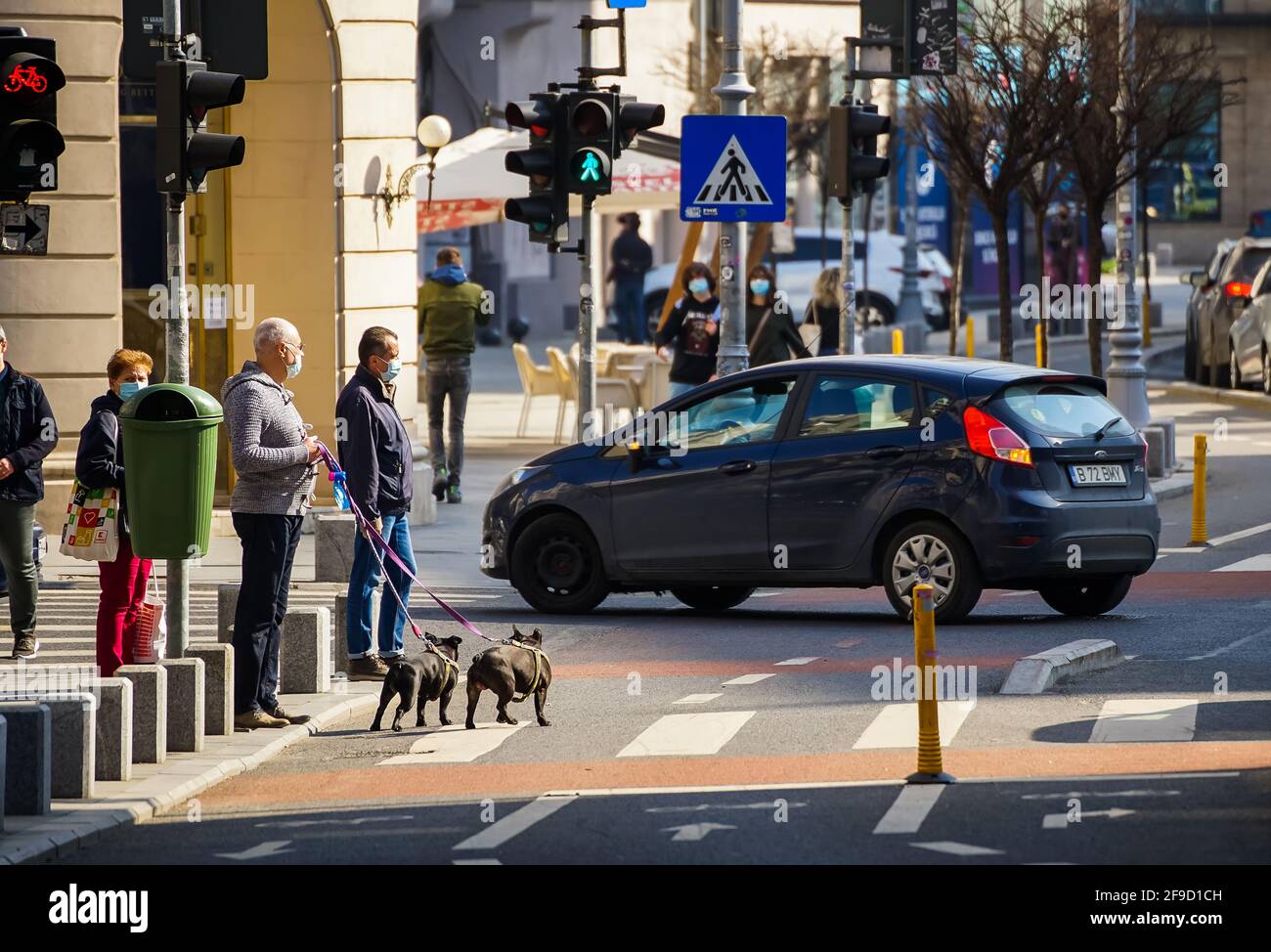 Bukarest, Rumänien - 01. April 2021: Die Menschen warten darauf, die Straße auf dem Radweg der Victory Avenue in Bukarest, Rumänien, zu überqueren. Stockfoto