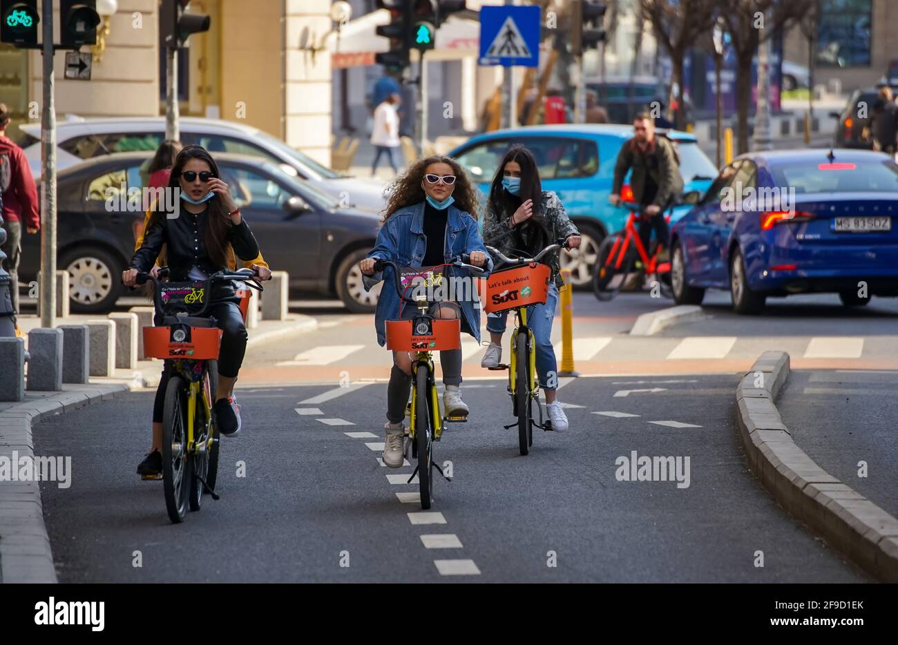Bukarest, Rumänien - 01. April 2021: Drei junge Frauen fahren auf dem Fahrradweg der Victory Avenue mit gemieteten Fahrrädern. Dieses Bild ist nur für redaktionelle Zwecke bestimmt. Stockfoto