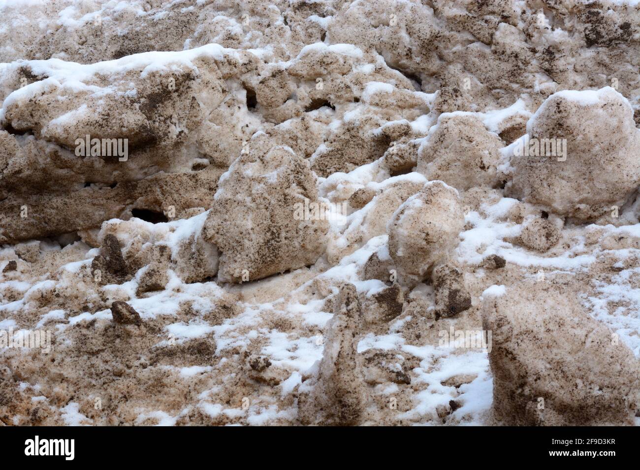 Texturierte Landschaft aus schmutzigem Schnee, der überhäuert wurde Zeit und Erosion Stockfoto