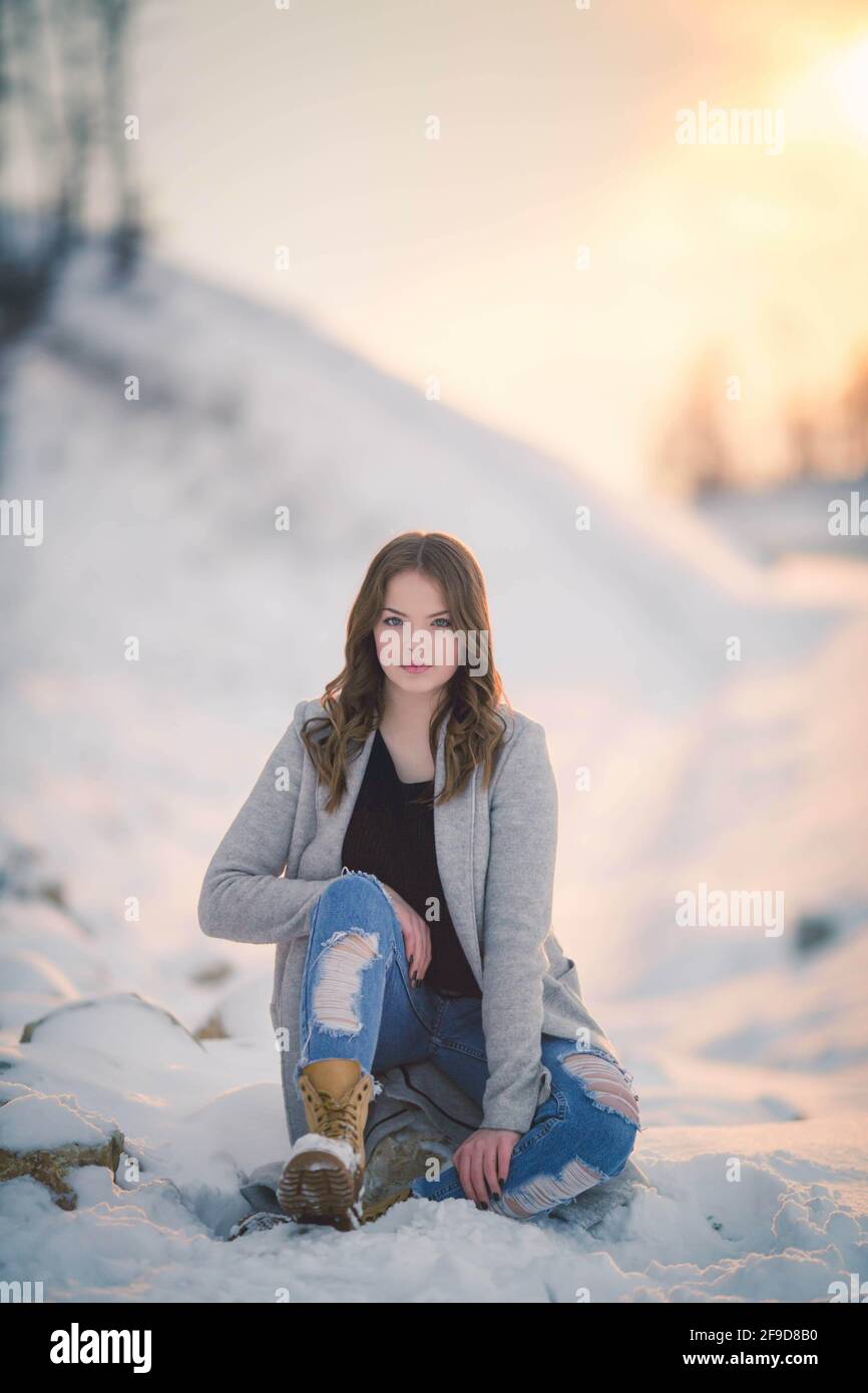 Schöne bosnisch kaukasische Frau in Mantel und Stiefel Blick auf Die Kamera mit ernsthafteren Gesicht im Schnee Stockfoto