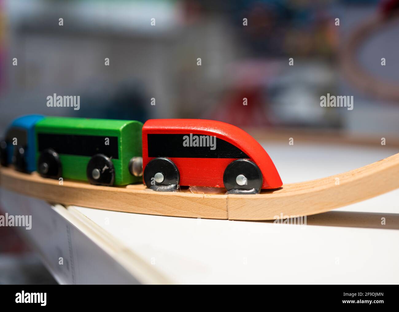 Der bunte Spielzeugzug ist auf der Holzbahn.; Hintergrund Stockfoto