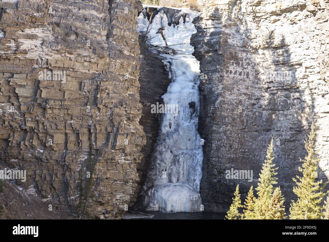 Bighorn Falls, ein Wasserfall in gefrorenen Bergen mit Rock Canyon-Landschaft an einem sonnigen Frühlingstag im Gebiet der Ya-Ha-Tinda Ranch in den Ausläufern von Alberta, Kanada Stockfoto