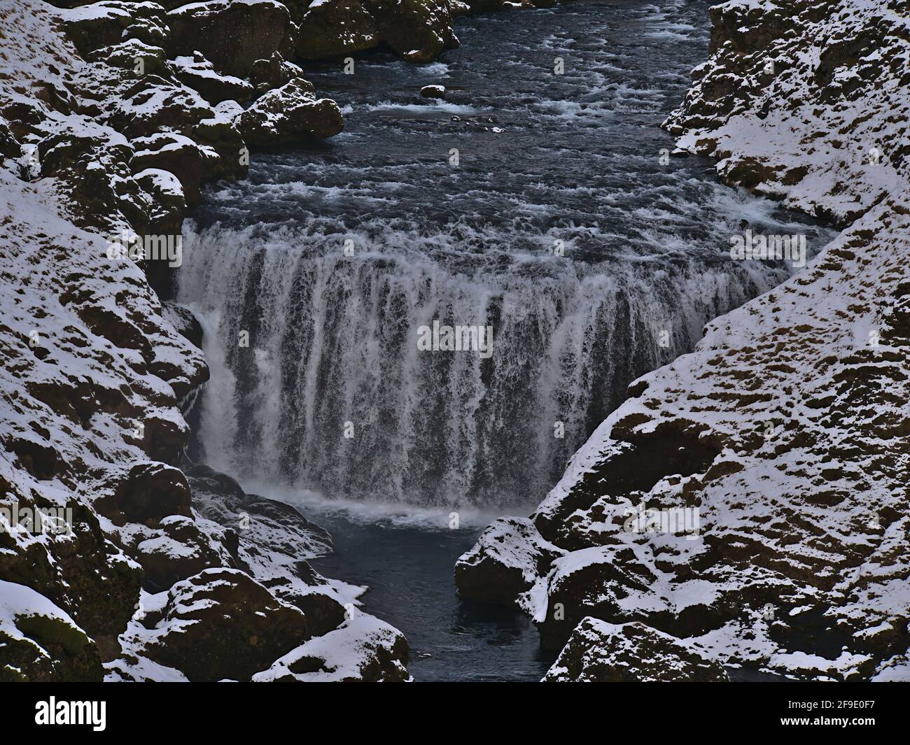 Nahaufnahme des Flusses Skógá mit Wasserfall Steinbogafoss in einer felsigen Schlucht in der Nähe von Fimmvörðuháls Trail im Winter mit schneebedeckten Felsen in Island. Stockfoto