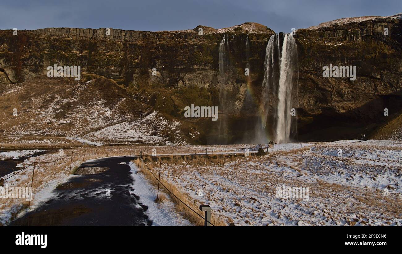 Atemberaubende Vorderansicht des berühmten Wasserfalls Seljalandsfoss, ein beliebtes Touristenziel im Süden Islands in der Nähe der Ringstraße (Route 1), mit Regenbogen. Stockfoto